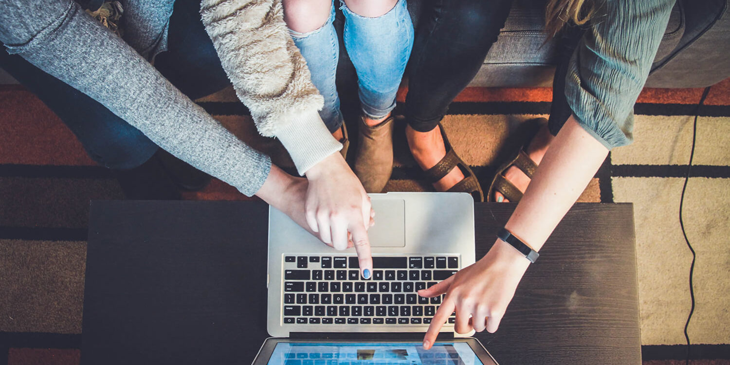 women pointing at a laptop screen