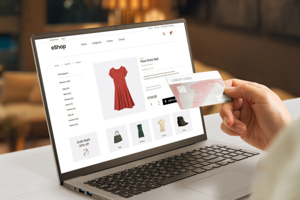 Shopping online with credit card concept modern ecommerce web page with woman clothes on laptop display