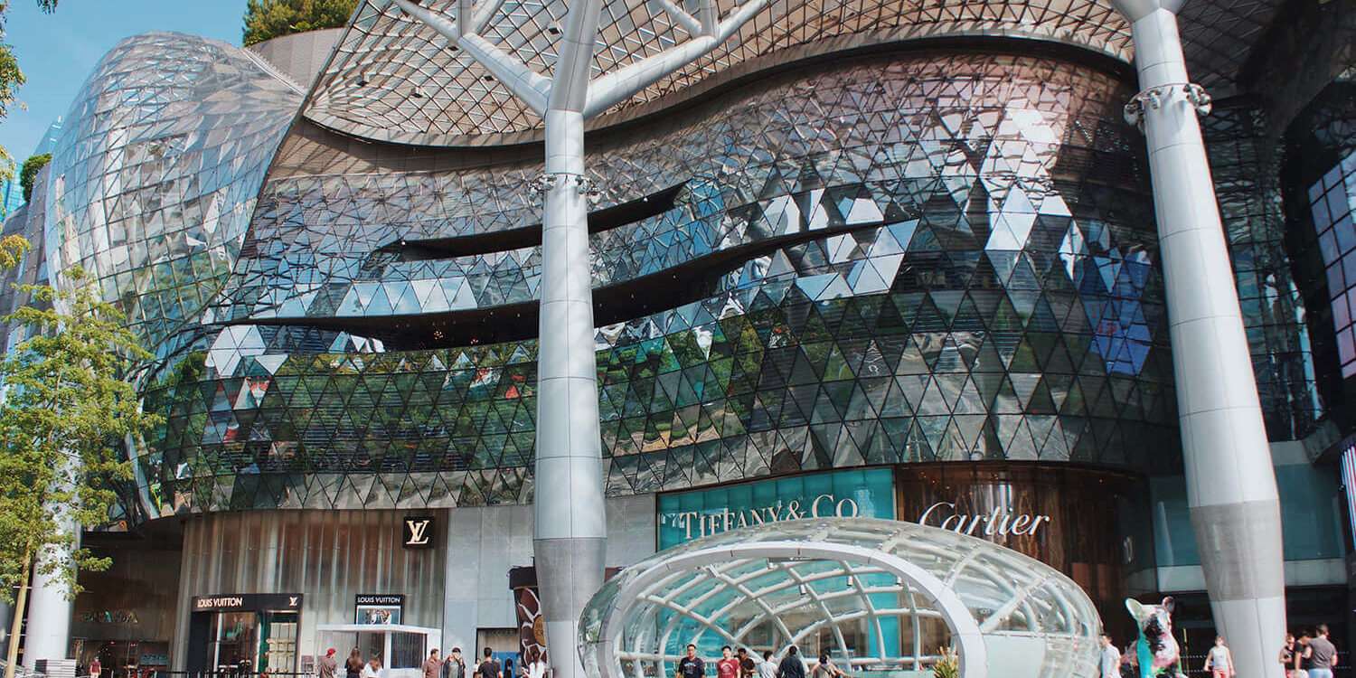 face a large mall with reflective windows and people walking
