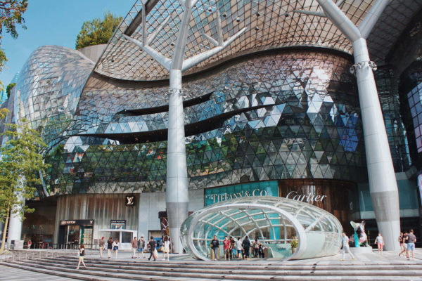 face a large mall with reflective windows and people walking