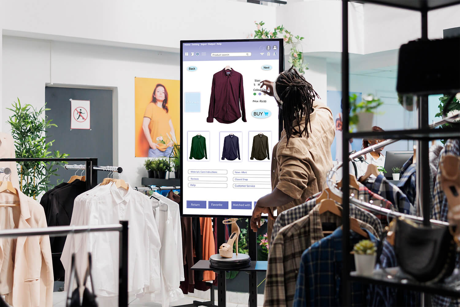 Man uses digital display to view shirts and jackets for sale in luxury retail shop.