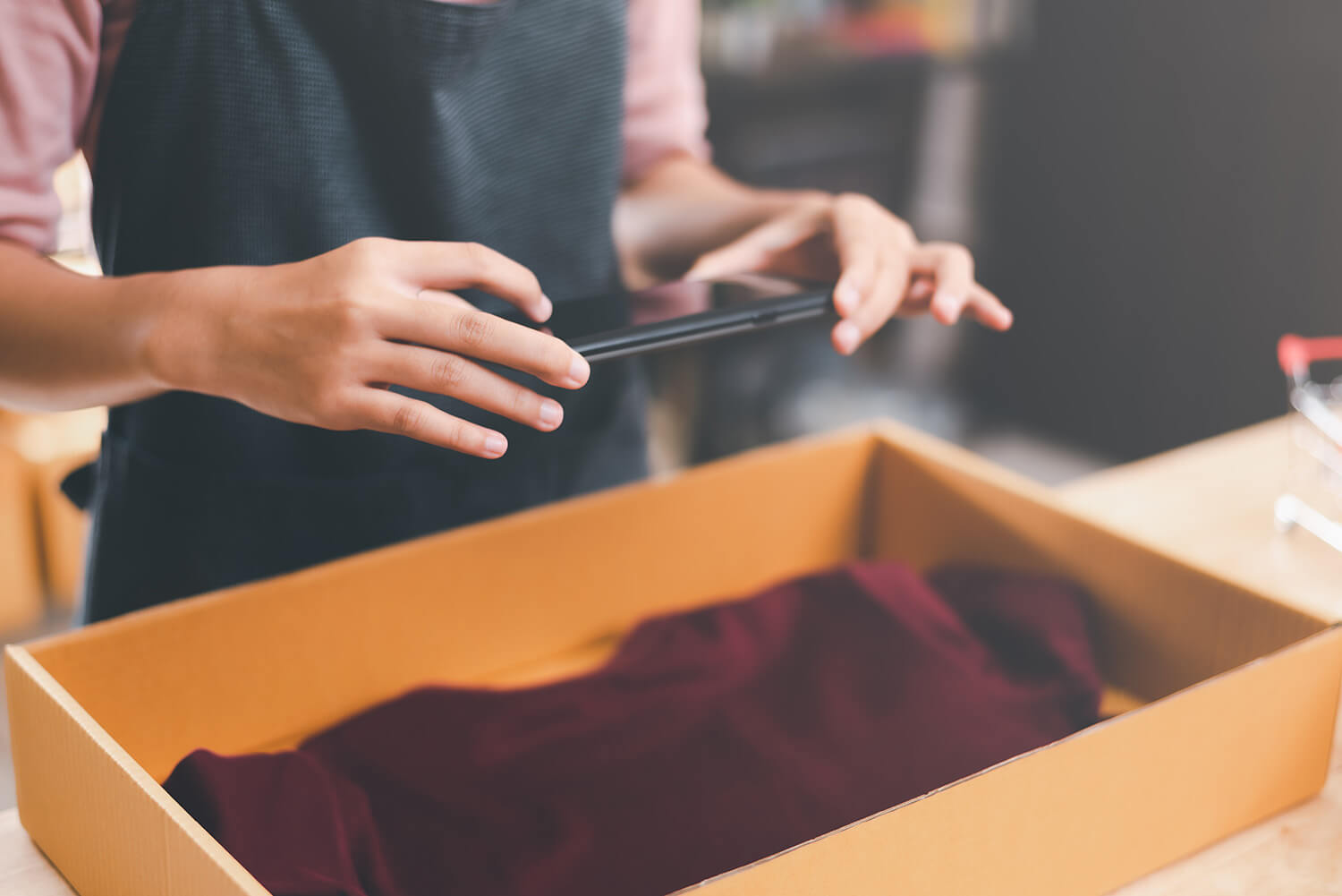 Store associate taking a photo of clothing in a box to be returned.