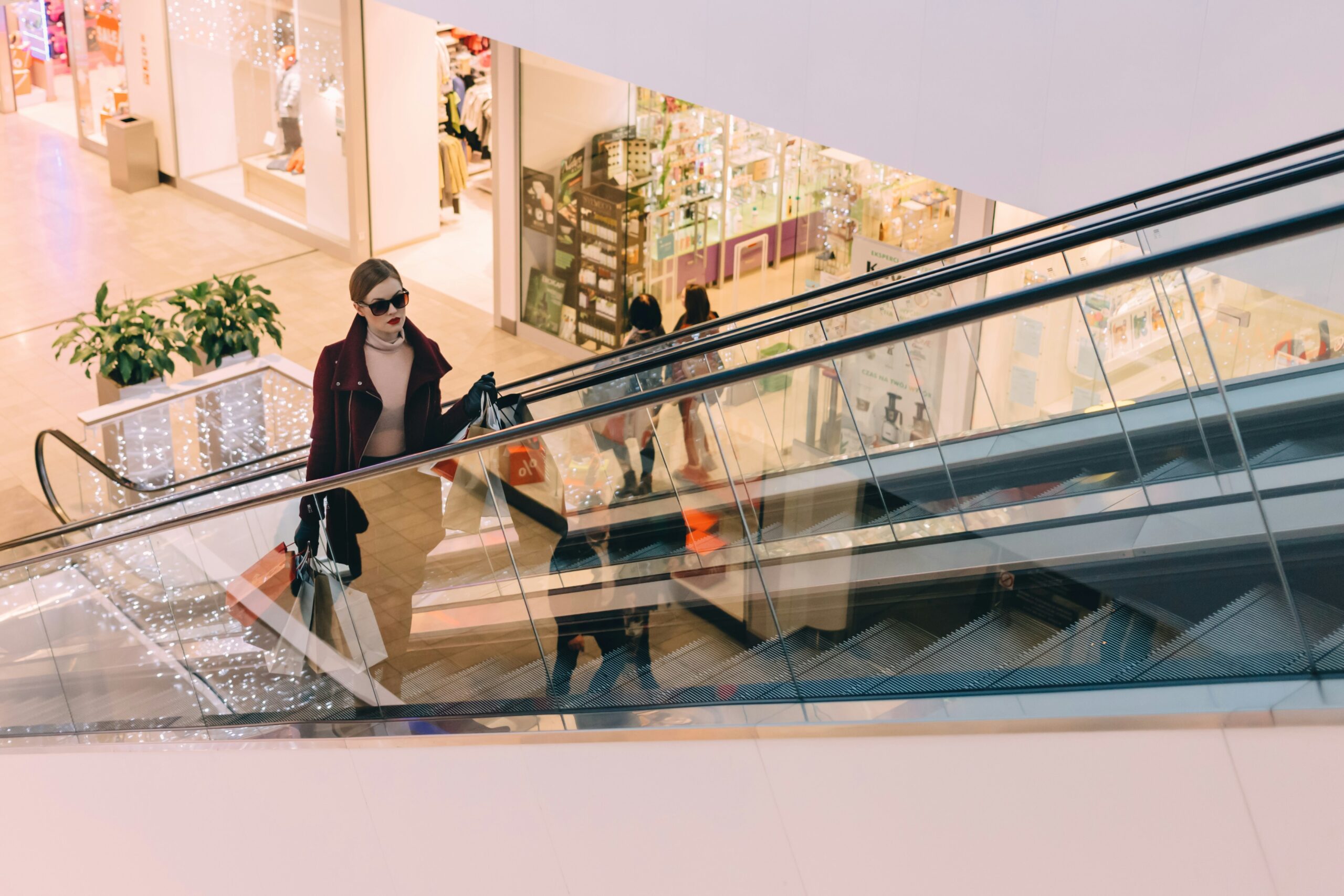 young woman with luxury shopping bags riding escalator